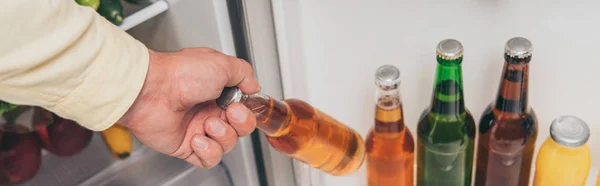 Ausgeschnittene Ansicht eines Mannes, der eine Flasche Bier aus dem Kühlschrank holt, Panoramaaufnahme — Stockfoto