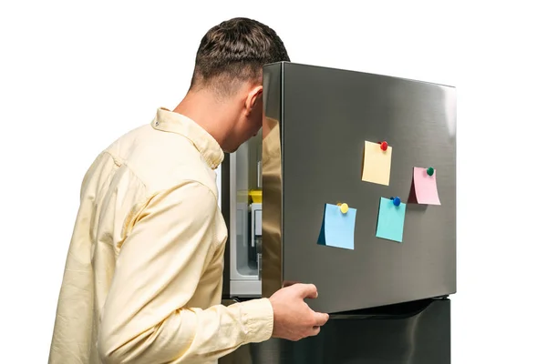 Ragazzo guardando in frigo aperto con note appiccicose isolato su bianco — Foto stock