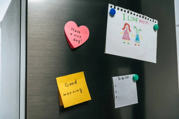 Desenho de família e notas com desejos pendurados na geladeira — Fotografia de Stock