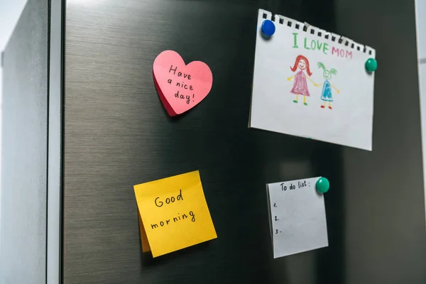 Drawing of family and notes with wishes hanging on fridge — Stock Photo