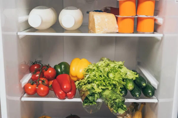 Открытый холодильник, полный свежих продуктов питания на полках — стоковое фото