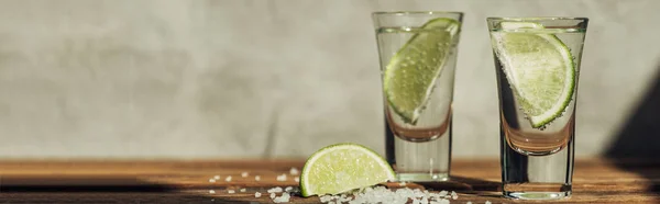 Tequila fresca con calce e sale sulla superficie di legno alla luce del sole, colpo panoramico — Foto stock