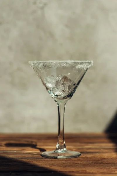 Martini glass with ice decorated with sugar on wooden surface in sunlight — Stock Photo