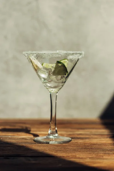 Vaso de martini con hielo, limón y lima decorado con azúcar en la superficie de madera a la luz del sol — Stock Photo