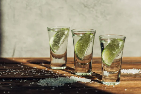 Tequila fresco con cal y sal en la superficie de madera a la luz del sol - foto de stock