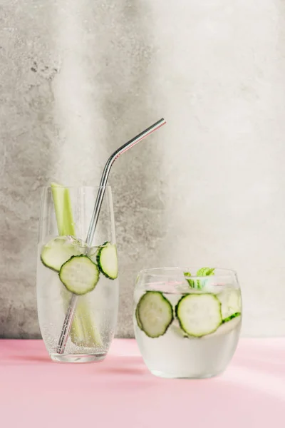 Fresh lemonade with ice, celery, straw and cucumber slices in sunlight — Stock Photo