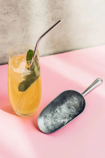 Fresh lemonade with ice, mint, straw near ice scoop in sunlight — Stock Photo