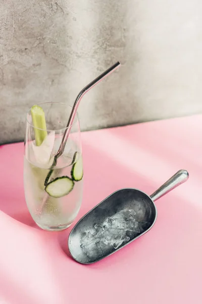 Fresh lemonade with ice, celery, straw and cucumber slices near ice scoop in sunlight — Stock Photo