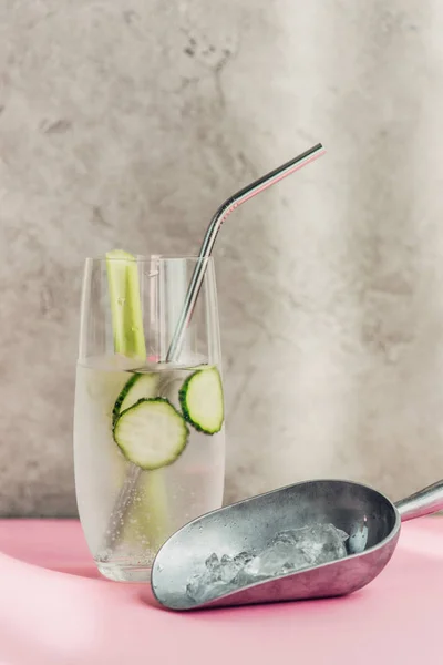 Fresh lemonade with ice, celery, straw and cucumber slices near ice scoop in sunlight — Stock Photo