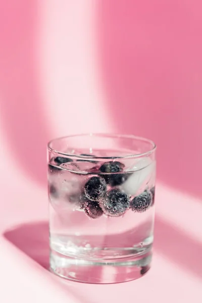 Fresh lemonade with ice and blueberries in sunlight on pink background — Stock Photo