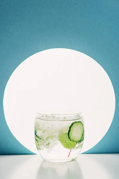 Frischer Gin Tonic mit Gurkenscheiben auf blauem Hintergrund mit Gegenlicht — Stockfoto