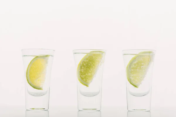 Tequila fresca con lima en fila aislada sobre blanco - foto de stock