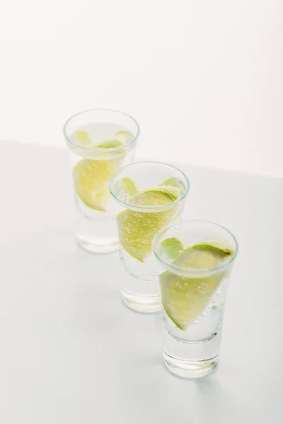 Frischer Tequila mit Limette in Reihe isoliert auf weiß — Stockfoto