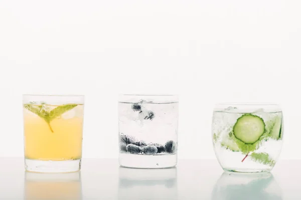 Bebidas refrescantes com mirtilos, hortelã, pepino e gelo isolados em branco — Fotografia de Stock