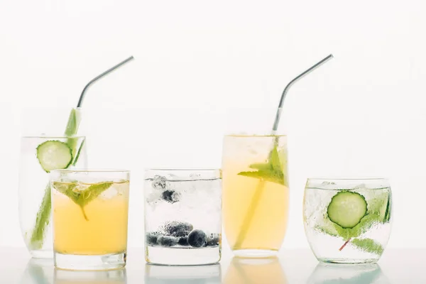 Refreshing drinks with blueberries, celery, straws, mint, cucumber and ice isolated on white — Stock Photo
