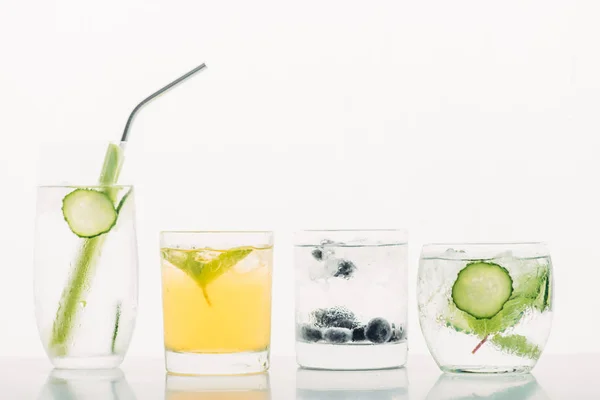 Bebidas refrescantes con arándanos, apio, paja, menta, pepino y hielo aislados en blanco - foto de stock