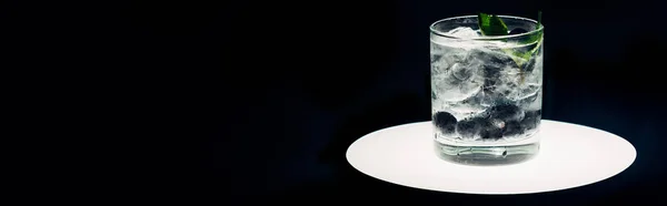 Refreshing lemonade with ice and blueberries on illuminated circle isolated on black, panoramic shot — Stock Photo