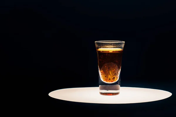 Alcohol shot on illuminated circle isolated on black — Stock Photo