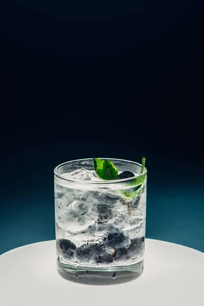 Refreshing lemonade with ice and blueberries on illuminated circle on black background — Stock Photo