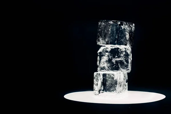Квадратні кубики льоду на освітленому колі ізольовані на чорному — стокове фото