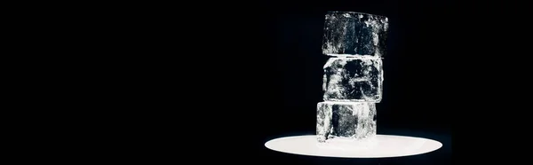 Square ice cubes on illuminated circle isolated on black, panoramic shot — Stock Photo