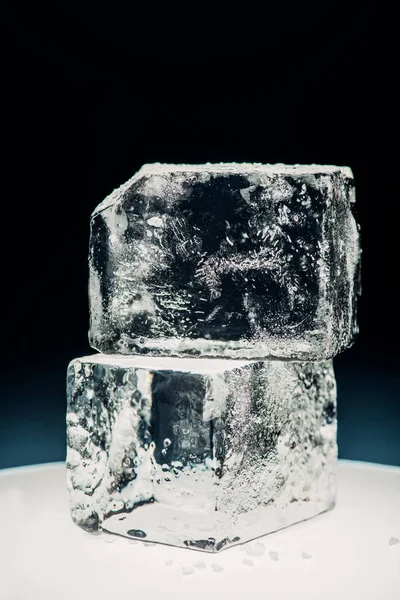 Vista de cerca de cubos de hielo cuadrados en círculo iluminado aislado en negro - foto de stock