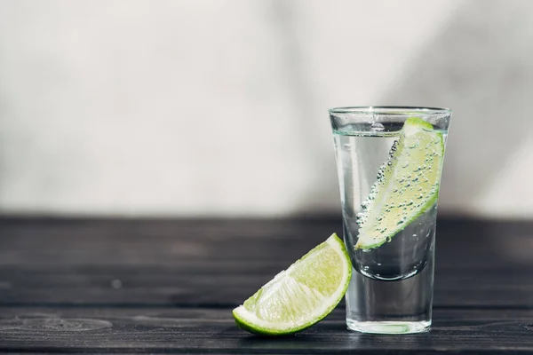 Fresh tequila with lime on wooden surface — Stock Photo