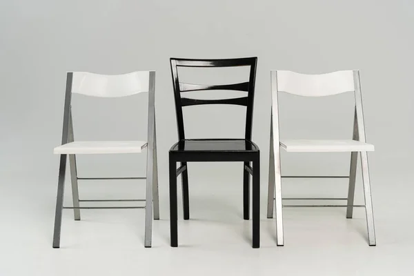 Three black and white chairs on grey background — Stock Photo