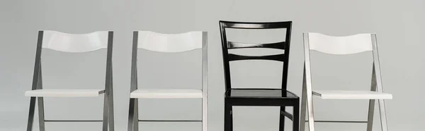 Sedie bianche e nere isolate su scatto grigio panoramico — Foto stock