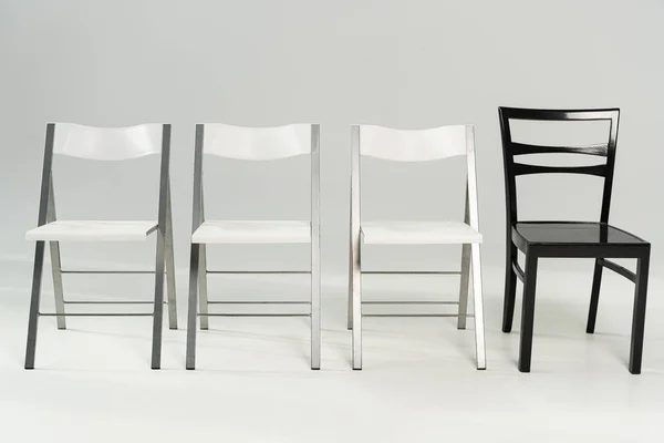 Modern white and black chairs on grey background — Stock Photo