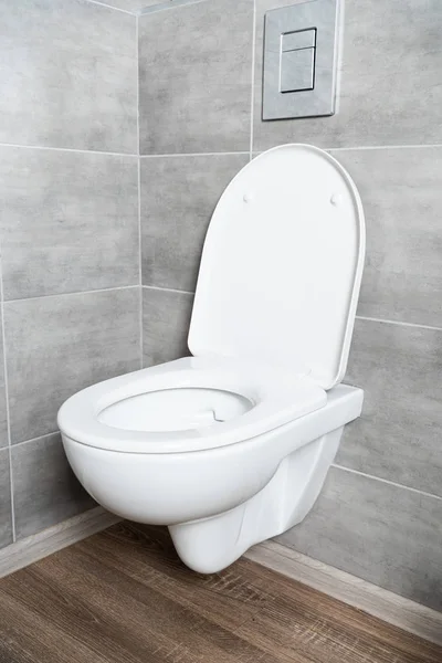 White toilet bowl with open seat in restroom with grey tile — Stock Photo