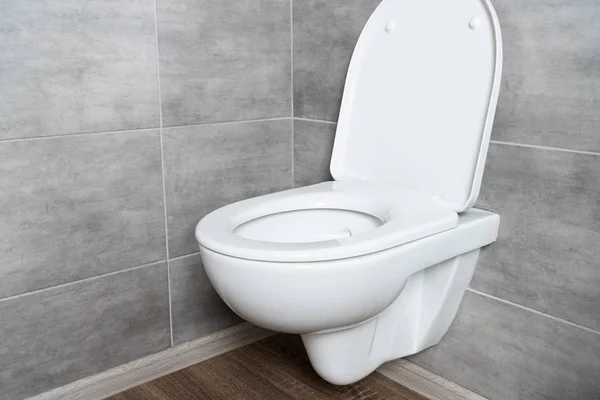 Clean toilet bowl with open seat in modern bathroom with grey tile — Stock Photo