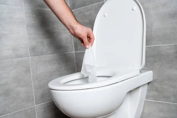 Vista recortada del hombre poniendo servilleta en el inodoro blanco en el baño - foto de stock