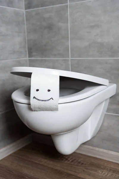 Papier toilette avec signe de sourire sur bol de toilette blanc dans la salle de bain moderne — Photo de stock