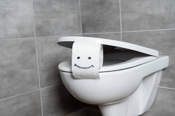 Papier toilette avec signe de sourire sur le bol de toilette dans les toilettes — Photo de stock