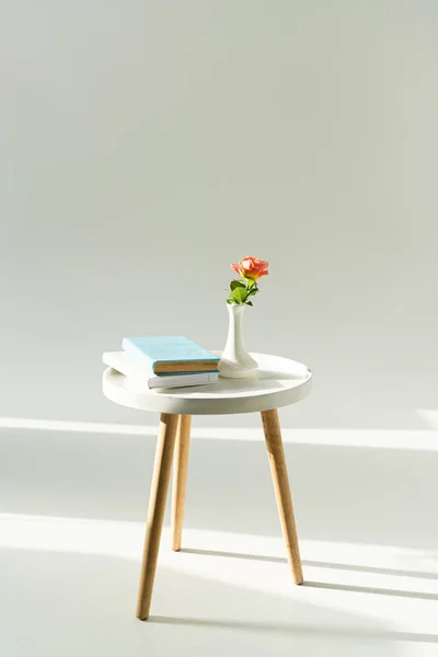 Trendy coffee table with flower in vase and books on grey background — Stock Photo