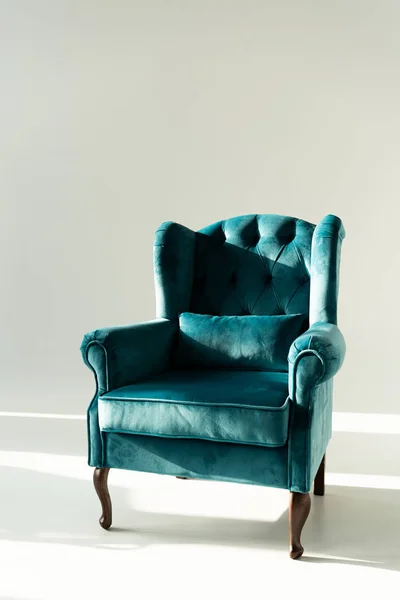 Modern turquoise armchair in sunlight on grey background — Stock Photo