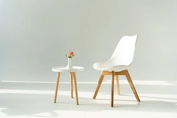 Chaise tendance blanche par table avec vase rose sur fond gris — Photo de stock