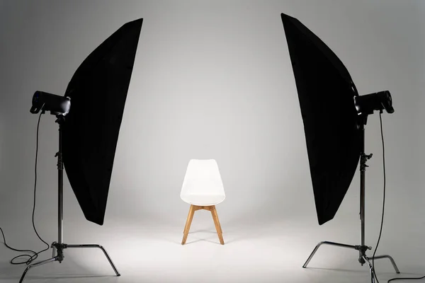 Silla moderna blanca con luz de estudio sobre fondo gris - foto de stock