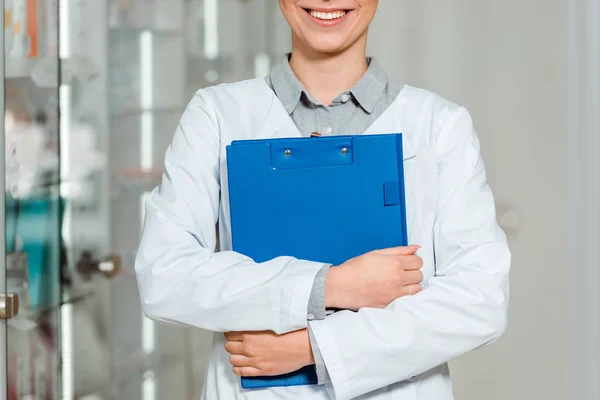 Cropped view of smiling pharmacist holding clipboard in drugstore — Stock Photo