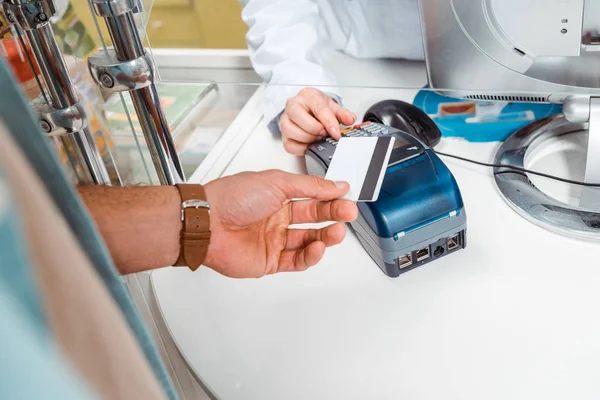 Ausgeschnittene Ansicht von Kunden, die mit Paypass in Apotheke bezahlen — Stockfoto