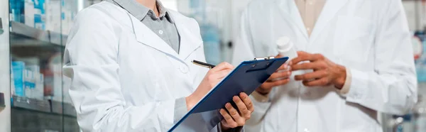 Cropped view of pharmacists with pills and clipboard in drugstore — Stock Photo