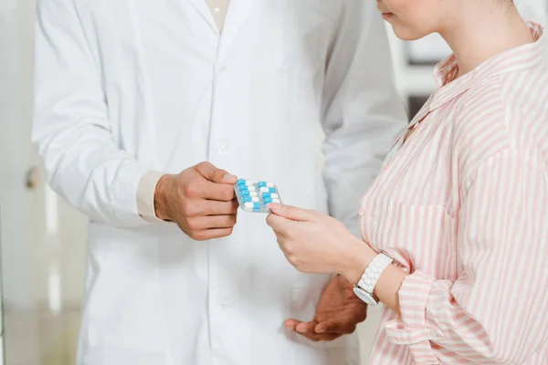 Cropped view of druggist giving to customer blister with pills — Stock Photo