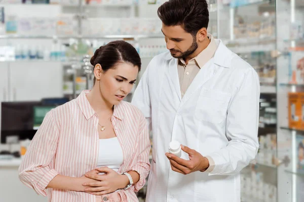 Pharmacist showing pills to customer with stomach disease in drugstore — Stock Photo