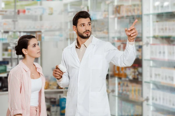 Droga com frasco de pílulas apontando para vitrine farmácia para o cliente — Fotografia de Stock