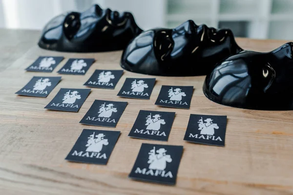 КИЕВ, УКРАИНА - 22 ноября 2019 года: игральные карты с мафиозными буквами возле черных масок для вечеринок — стоковое фото