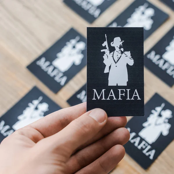 KYIV, UKRAINE - 22 NOVEMBRE 2019 : vue recadrée d'un homme tenant une carte à jouer noire avec des lettres de la mafia — Photo de stock