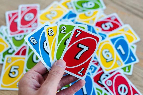 KYIV, UCRANIA - 22 de noviembre de 2019: vista recortada del hombre sosteniendo colorido uno jugando a las cartas - foto de stock