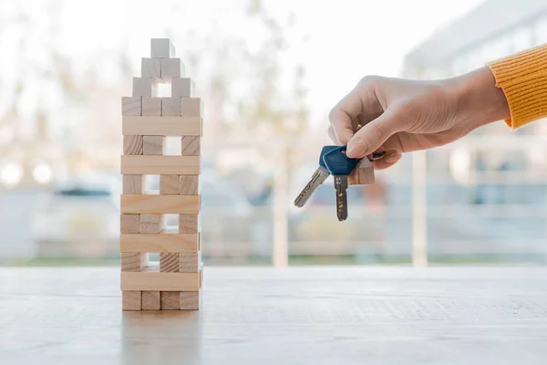 KYIV, UCRANIA - 22 de noviembre de 2019: vista recortada de la mujer sosteniendo las llaves bloques torre de madera juego - foto de stock