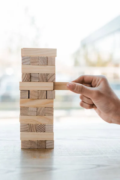 KYIV, UCRANIA - 22 de noviembre de 2019: vista recortada de la mujer que toma el bloque mientras juega al juego de la torre de madera en casa - foto de stock